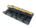 Black metal bass guitar bridge with four gold-colored saddles and adjustment screws.