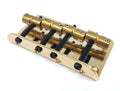 Gold-colored metal guitar bridge with four adjustable saddles and screws on white background.