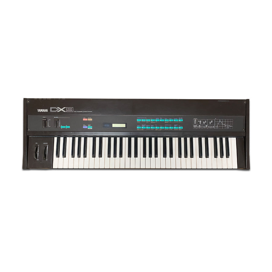 Black Yamaha DX9 synthesizer keyboard with sliders, buttons, and keys.