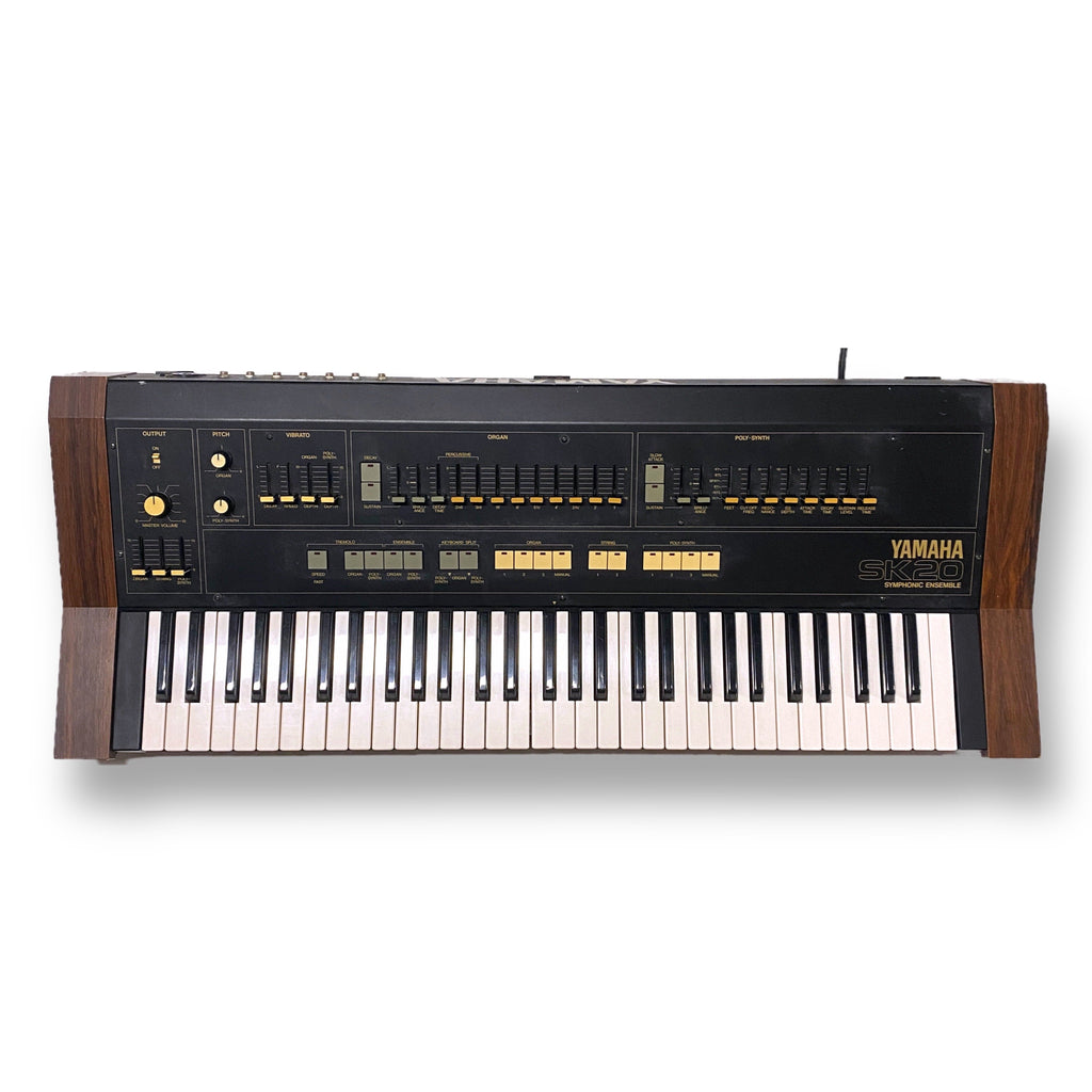 Top view of a Yamaha SK-20 keyboard synthesizer with wooden side panels and various sliders and buttons.
