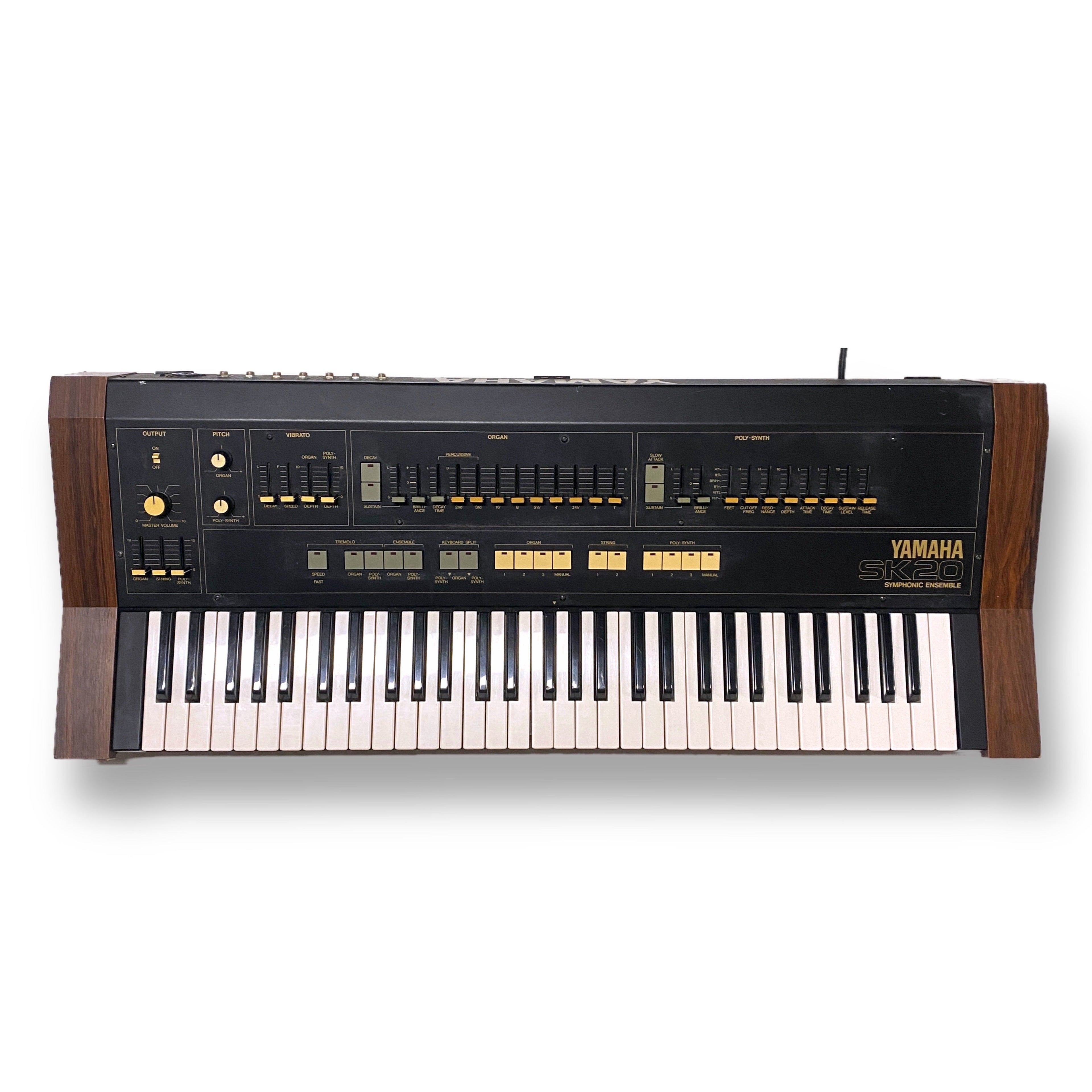 Top view of a Yamaha SK-20 keyboard synthesizer with wooden side panels and various sliders and buttons.