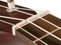 Close-up of a slotted white guitar or ukulele nut on a wood fretboard with white strings attached.