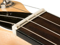 Close-up image of a guitar nut on a stringed instrument neck with three metal strings.