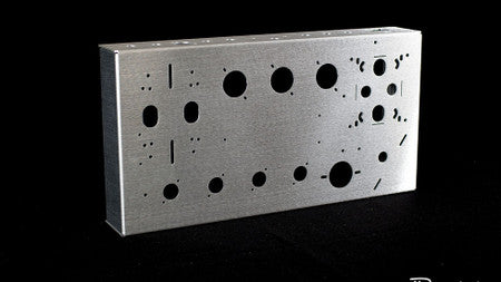 Silver metallic rectangular amplifier chassis with multiple round and oval cutouts on a black background.