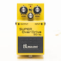 A bright yellow Boss SD-1W Super Overdrive compact guitar pedal, showing three top-mounted knobs (Level, Tone, Drive), a small mode switch, a CHECK indicator LED, and a large footswitch pedal.
