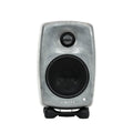 Front view of a compact grey Genelec speaker with protective black speaker grills on two drivers.