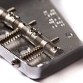 Close-up of a metal guitar bridge with adjustable saddles and springs on a white background.