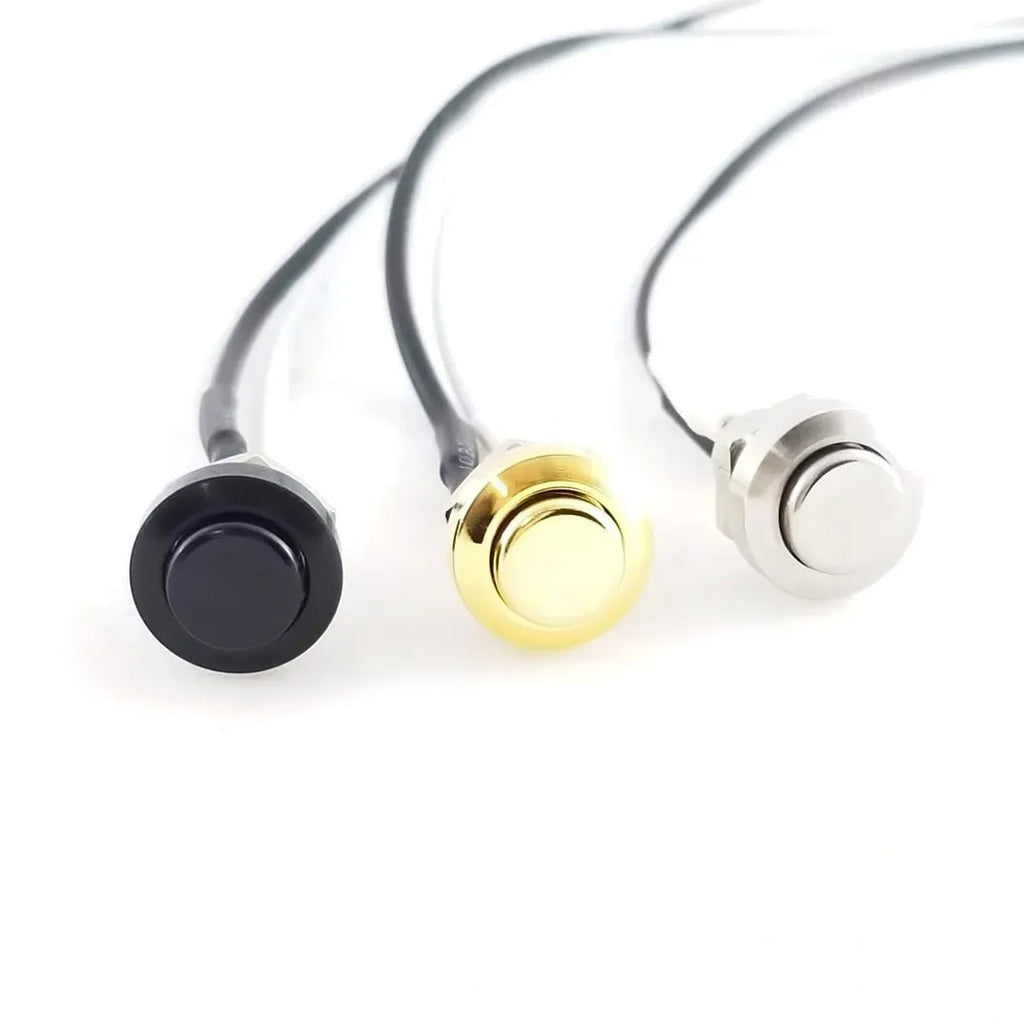 Three metal push button switches with attached black wires in black, gold, and silver colors.