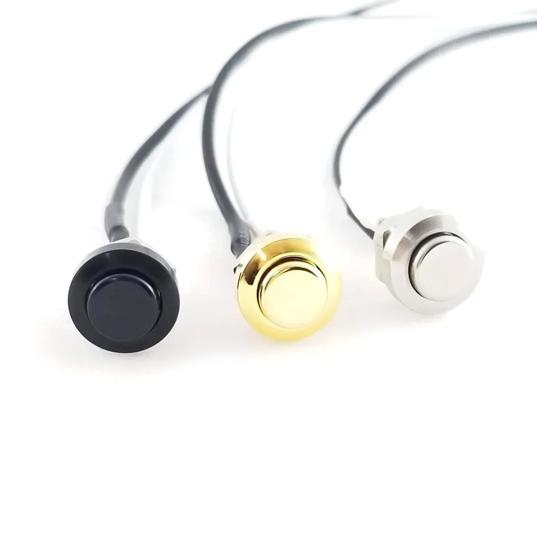 Three metal push button switches with attached black wires in black, gold, and silver colors.