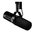Black dynamic microphone with foam windscreen and mounting bracket showing brand name SHURE.