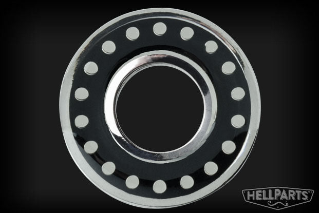 Circular metal washer with black and silver finish and dots around the inner ring on black background