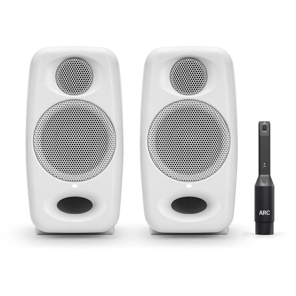 Pair of white studio monitor speakers with a black ARC calibration device placed beside them.