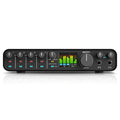 Front view of black MOTU audio interface with knobs, buttons, headphone jacks, and color level meters on screen.