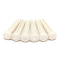 Six white guitar bridge pins with small white pearl-like dots on top arranged in a row on a white background.