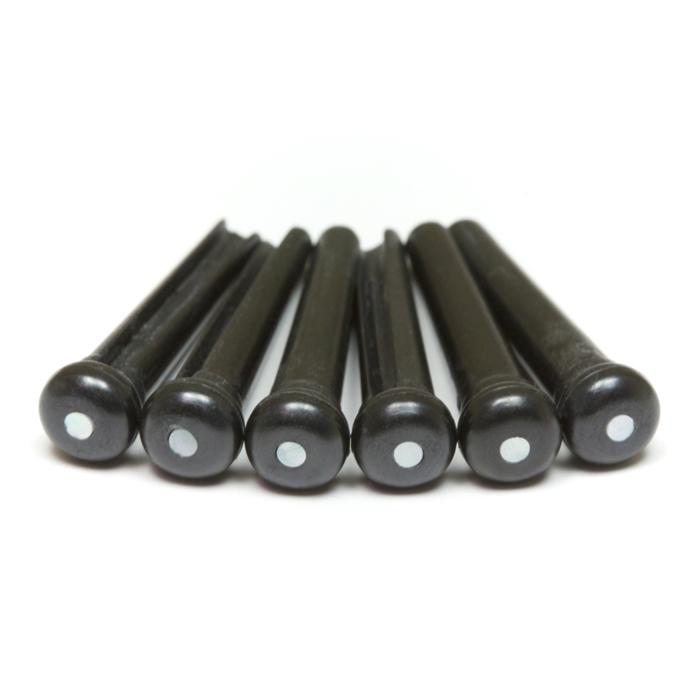 Six black guitar bridge pins each with a small white dot on the top, arranged side by side on a white background.