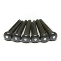 Six black guitar bridge pins each with a small white dot on the top, arranged side by side on a white background.