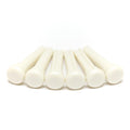 Six white plastic cylindrical pins with rounded heads arranged in a row on a white surface.