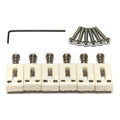 Six white guitar saddles with metal screws and an L-shaped hex key arranged on a white background.