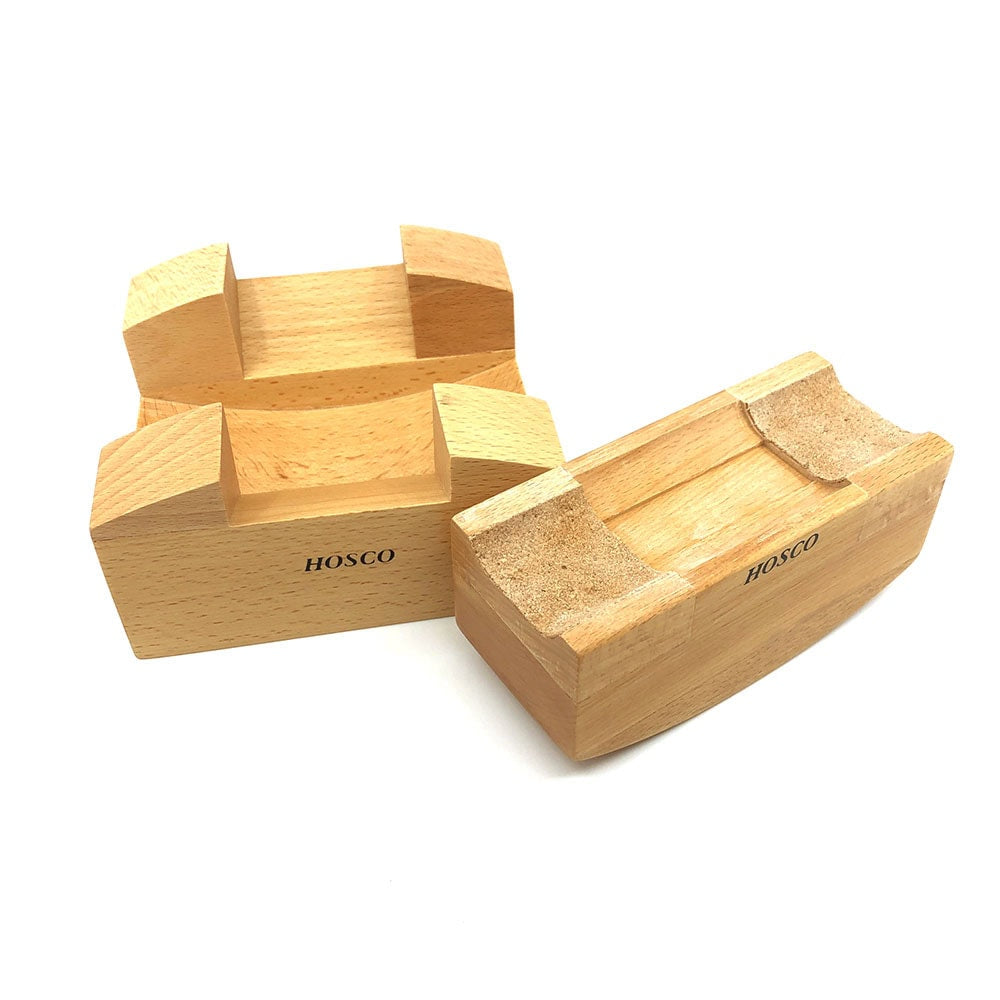 Two wooden blocks with angled cutouts and cork padding labeled Hosco, likely for support use.