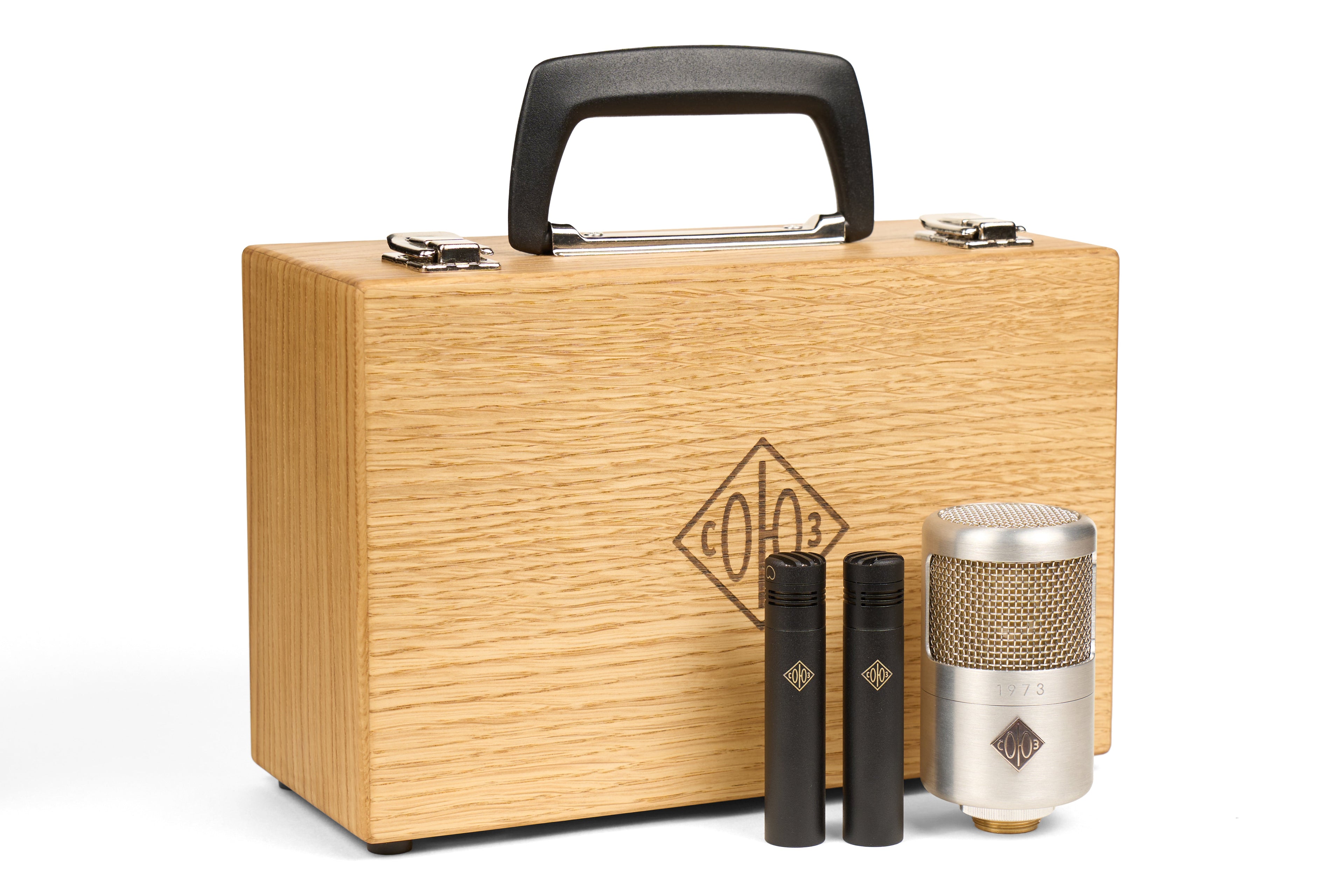 Wooden carrying case with two small black microphones and one larger silver microphone with mesh grille.
