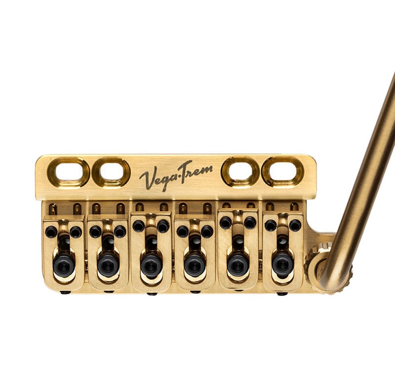 Gold-colored metal tremolo bridge with six string saddles and attached tremolo arm, labeled Vega-Trem.