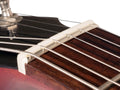 White slotted guitar nut mounted on guitar neck with strings passing through slots.